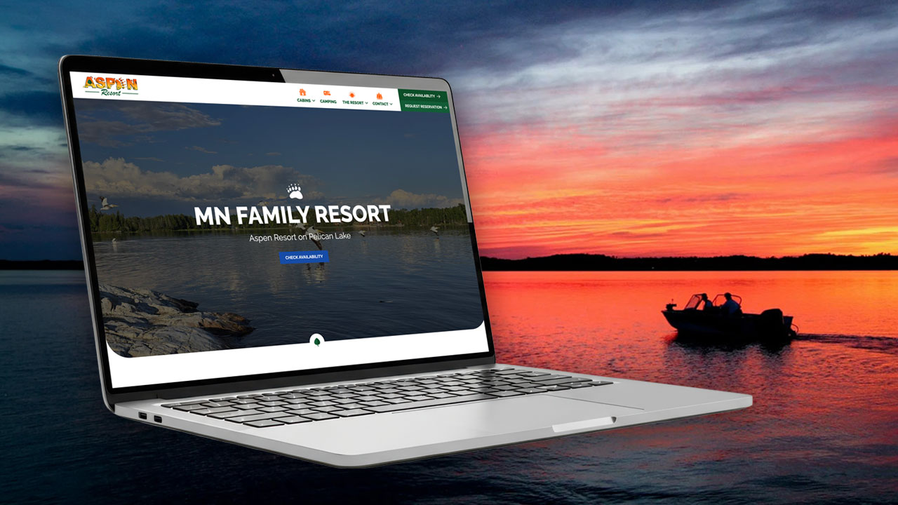 Laptop showing Aspen Resort website over lake sunset
