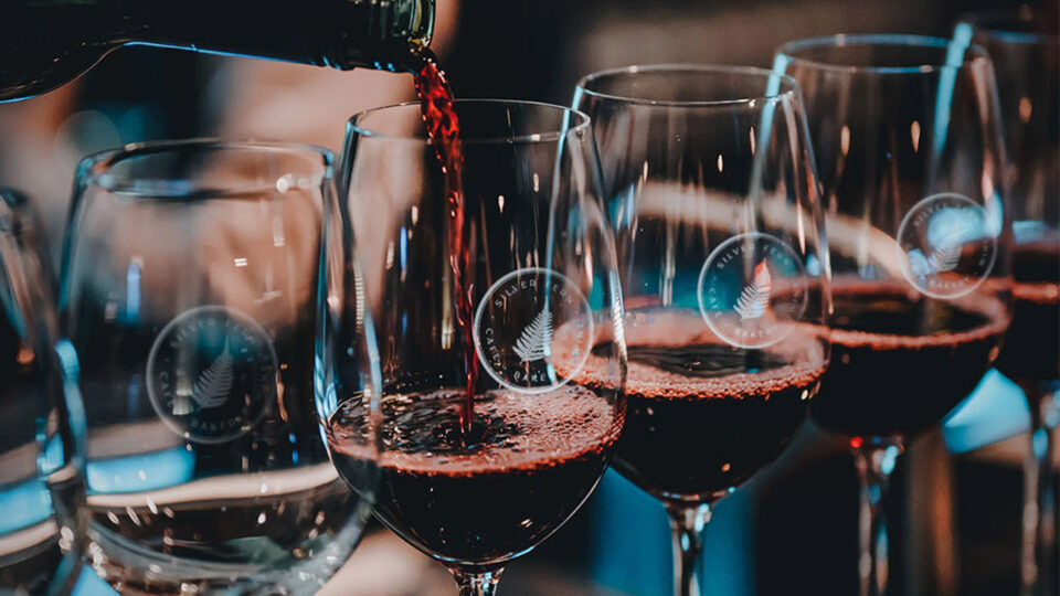 Pouring red wine into glasses at a winery.