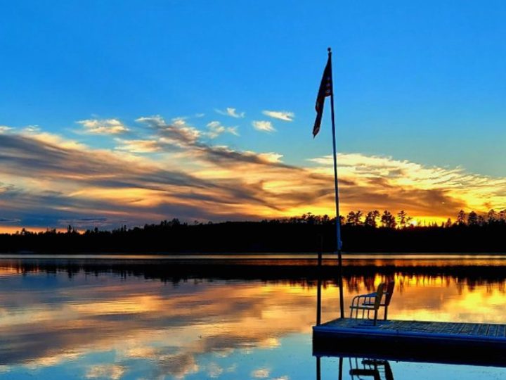 American flag on dock over calm lake sunset
