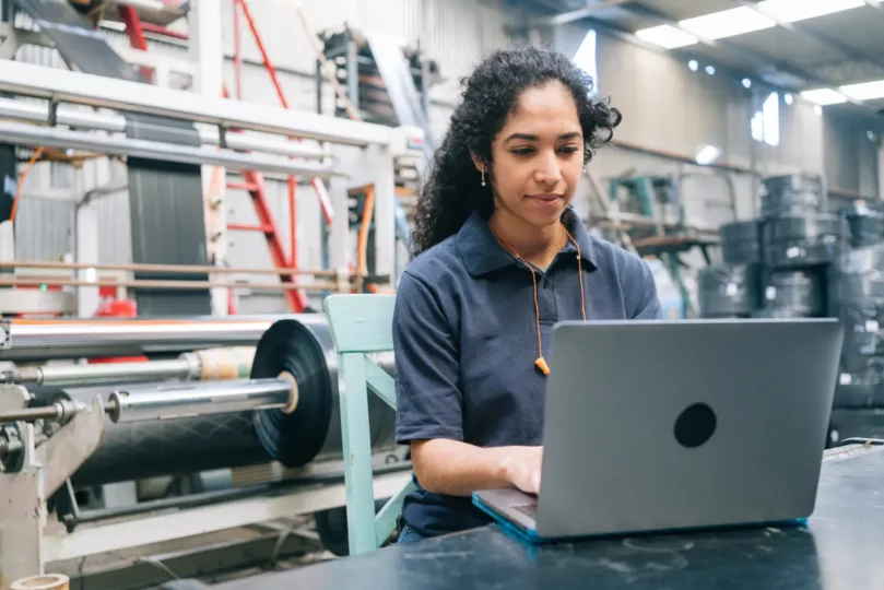 Person working on laptop in industrial setting.