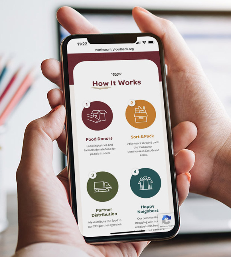 Hand holding smartphone displaying North Country Food Bank website