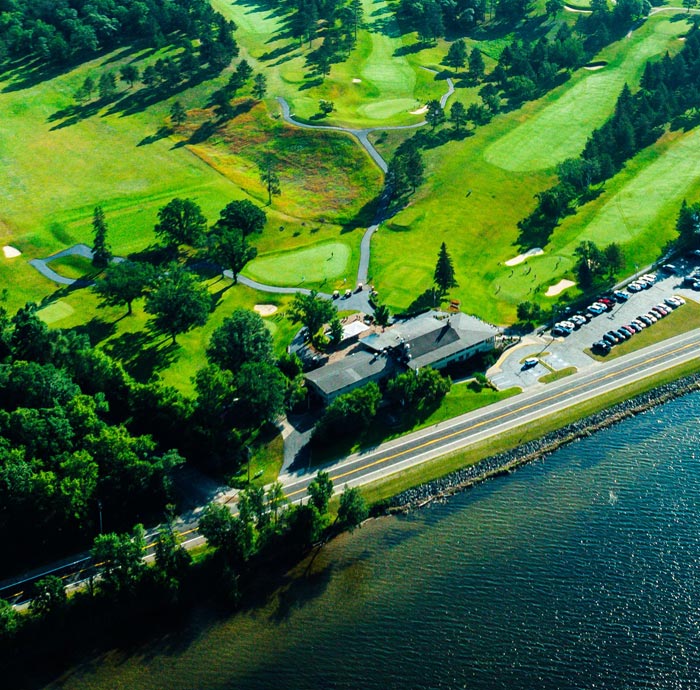 Aerial view of lush green golf course, lakeside road.